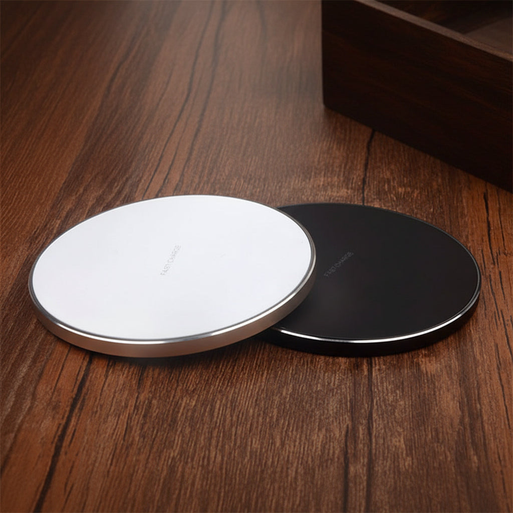 Two wireless charging pads, one white and one black, on a wooden surface.