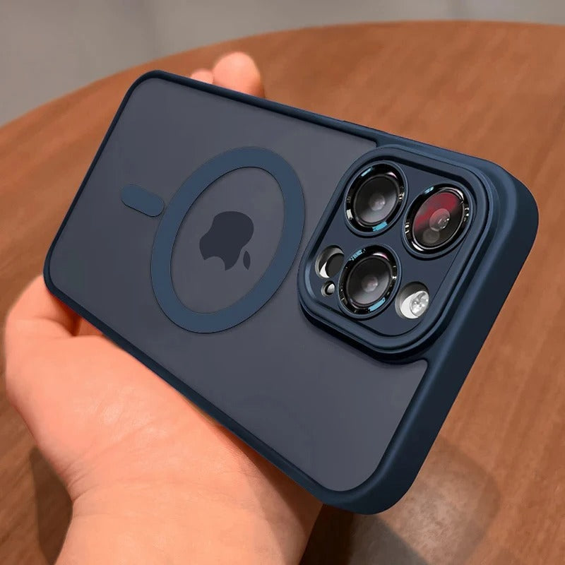 A navy blue protective phone case with a MagSafe ring and camera cutout, held in a hand over a wooden surface.