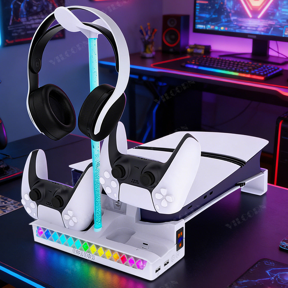 A white and black gaming accessory stand holding a PlayStation 5 console, two DualSense controllers, and a pair of over-ear headphones, set on a desk in a gaming room with colorful ambient lighting.