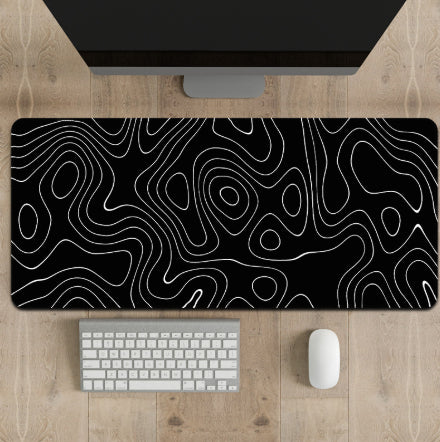 Black desk mat with white line pattern on a wooden desk with computer and accessories.