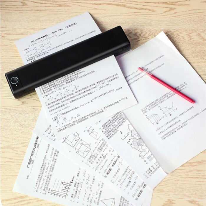 Black handheld printer on top of papers with a red pen on a wooden surface