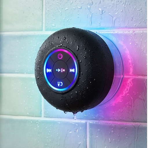 Black bluetooth speaker with colorful lights on a tiled shower wall