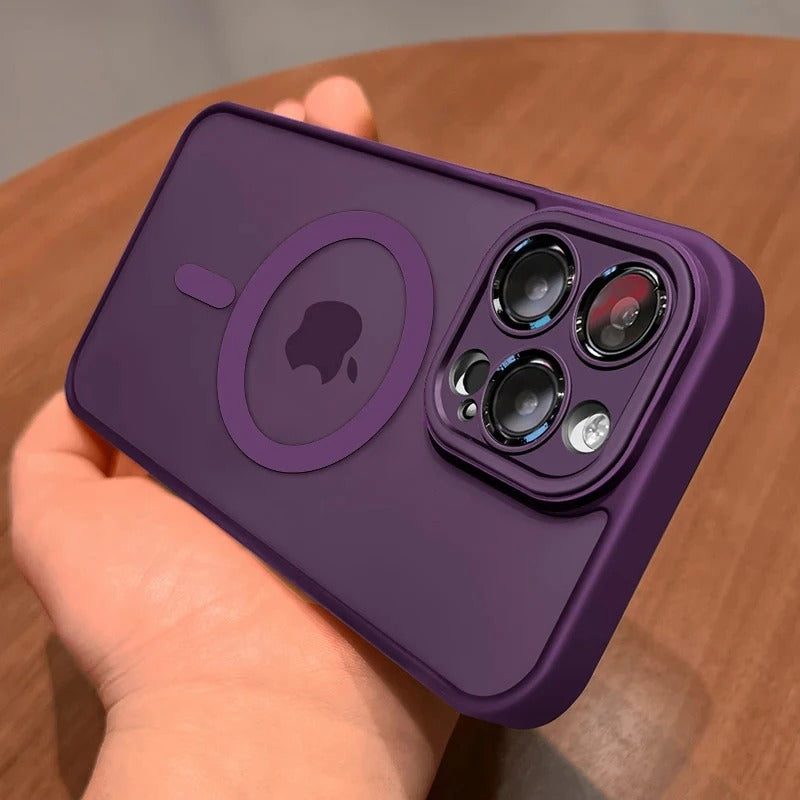 A dark purple protective phone case with a MagSafe ring and camera cutout, held in a hand over a wooden surface.