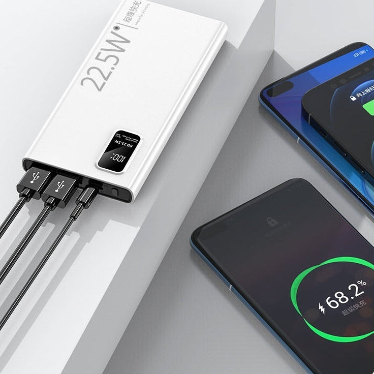 Power bank with multiple charging cables and two smartphones showing charging status on a light gray background