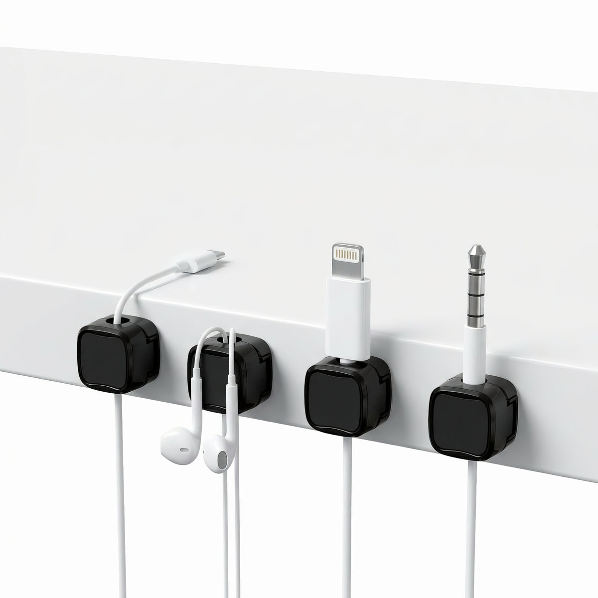 Magnetic cable management clips holding charging cables and earphones attached to desk edge